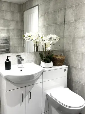 a bathroom with a sink and a toilet and flowers at Summerlee Gateaway in Coatbridge