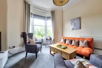 a living room with an orange couch and a table at Maya's Holiday Homes in Glasgow