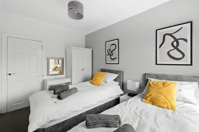 a bedroom with two beds with yellow pillows at Grangeburn Residence - 2 bedroom home with parking in Falkirk
