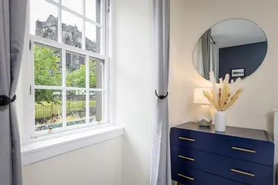 a mirror and a blue dresser in a room with a window at Castle Esplanade Apartment in Stirling