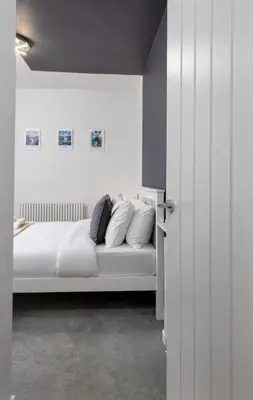 a bedroom with a bed with white sheets and pillows at Castle Esplanade Apartment in Stirling