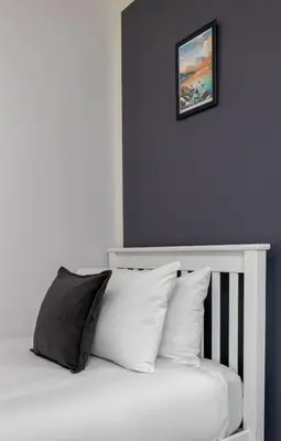 a bed with white pillows and a picture on the wall at Castle Esplanade Apartment in Stirling