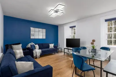a living room with blue walls and a blue couch at Castle Esplanade Apartment in Stirling