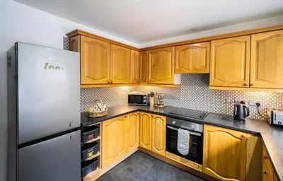 a kitchen with wooden cabinets and a refrigerator at 12 & 14 On the Hill Aberfoyle, twin holiday cottages in Scenic Loch Lomond & Trossachs National Park in Aberfoyle