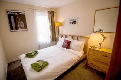 a bedroom with a bed with a mirror and a lamp at 12 & 14 On the Hill Aberfoyle, twin holiday cottages in Scenic Loch Lomond & Trossachs National Park in Aberfoyle