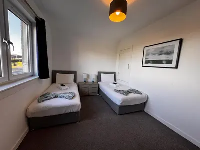 two twin beds in a room with a window at Loch Ore View in Kelty