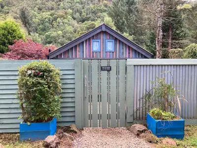 a small house with a fence and two plants at The Old Shed in Benderloch