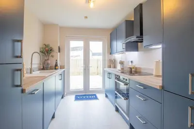 a kitchen with blue cabinets and a large window at Hawick Apartment- 2-Bed in Coatbridge, Mins from Motorway to Glasgow in Old Monkland