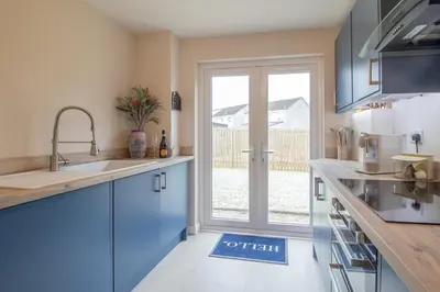 a kitchen with blue cabinets and a sliding glass door at Hawick Apartment- 2-Bed in Coatbridge, Mins from Motorway to Glasgow in Old Monkland