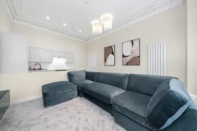 a living room with a blue couch and a table at Paisley Road Courtyard in Glasgow