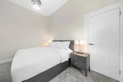a bedroom with a white bed and a nightstand with a bed sidx sidx sidx at Paisley Road Courtyard in Glasgow