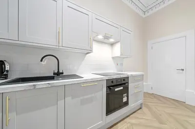 a white kitchen with white cabinets and a sink at Paisley Road Courtyard in Glasgow