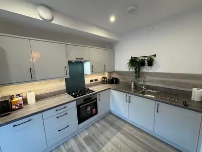 a large kitchen with white cabinets and a sink at Modern Flat in Glasgow City FREE Parking & Wifi in Glasgow