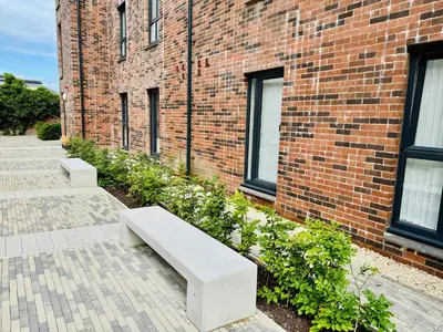 a bench sitting in front of a brick building at Modern Flat in Glasgow City FREE Parking & Wifi in Glasgow