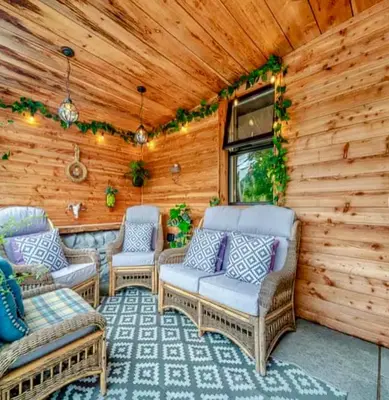 a porch with wicker chairs and a wooden wall at Creebank Cottage with river view in Newton Stewart
