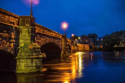 an old stone bridge over a river at night at Creebank Cottage with river view in Newton Stewart