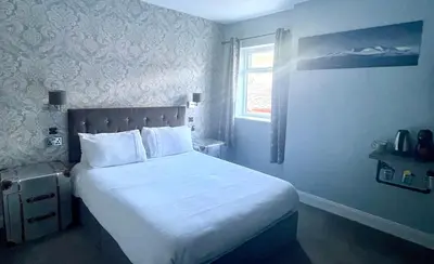 a bedroom with a large white bed with a window at Burlington Guest House in Whiting Bay