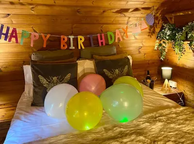 a bunch of balloons on a bed with a happy birthday banner at Loch Lomond Hideaways- Luxury Cabins with Jacuzzi Hot Tubs for Two in Drymen