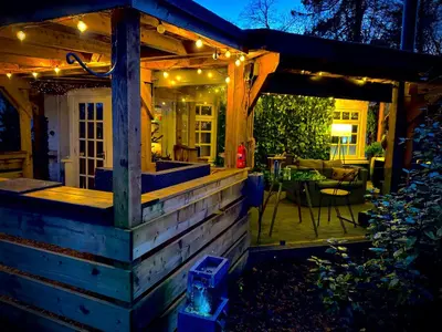 a wooden house with a deck with a table and a patio at Loch Lomond Hideaways- Luxury Cabins with Jacuzzi Hot Tubs for Two in Drymen