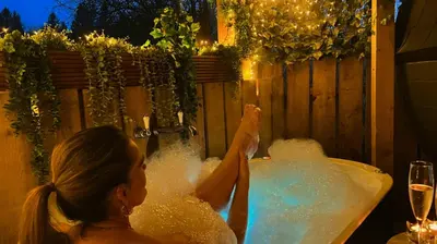 a woman sitting in a bathtub filled with water at Loch Lomond Hideaways- Luxury Cabins with Jacuzzi Hot Tubs for Two in Drymen