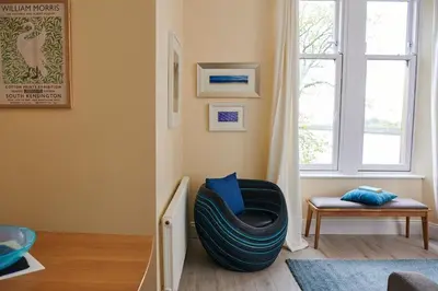 a living room with a chair and a window at Swan Cove Apartment Gourock in Gourock