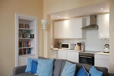 a living room with a couch and a kitchen at Swan Cove Apartment Gourock in Gourock