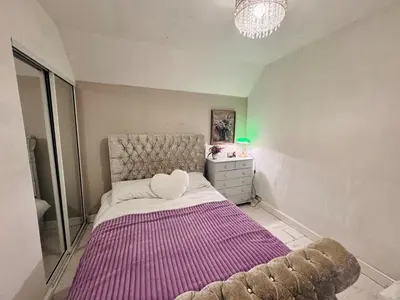 a bedroom with a large bed with a purple blanket at Bright 3 bedroom house with private garden near Edinburgh - Woodside home in Rosyth