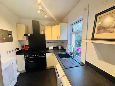 a small kitchen with a sink and a stove at Bright 3 bedroom house with private garden near Edinburgh - Woodside home in Rosyth