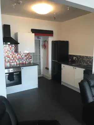 a kitchen with white cabinets and black appliances at Culag Lochside Self Catering in Luss