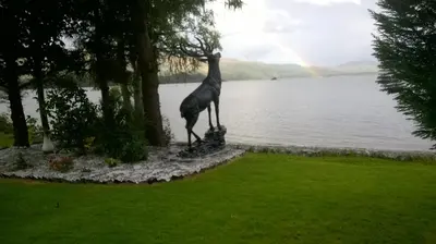 a statue of a giraffe standing next to a lake at Culag Lochside Self Catering in Luss