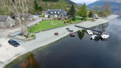 an aerial view of a house with a boat in the water at Culag Lochside Self Catering in Luss