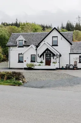 a white house with a bench in front of it at Inn at Port nan Gael in Pennyghael