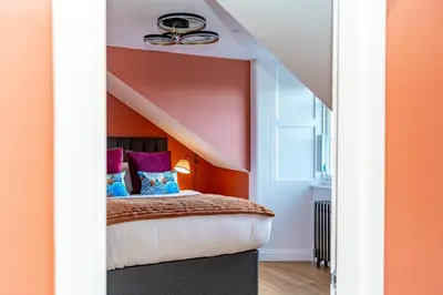 a bedroom with a bed with an orange wall at Dragon Suites Luxury Apartments at 8 Albyn Place in Edinburgh