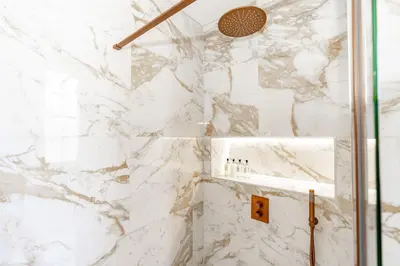a bathroom with white marble walls and a shower at Dragon Suites Luxury Apartments at 8 Albyn Place in Edinburgh