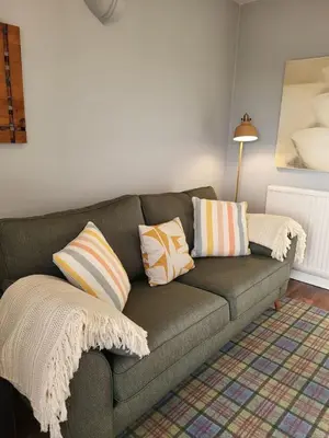 a living room with a gray couch with pillows at The Wee House -Coorie Doon Stays in Troon