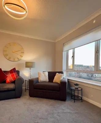 a living room with a couch and a clock on the wall at Chic & Cozy 2-Bed Flat in Glasgow - Free Parking in Glasgow