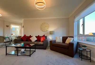 a living room with two couches and a clock on the wall at Chic & Cozy 2-Bed Flat in Glasgow - Free Parking in Glasgow