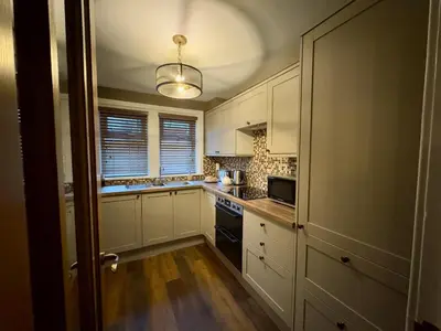 a kitchen with white cabinets and a stove top oven at Cochrane House in Stirling