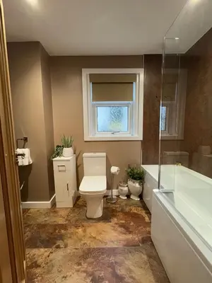a bathroom with a toilet and a tub and a window at Cochrane House in Stirling
