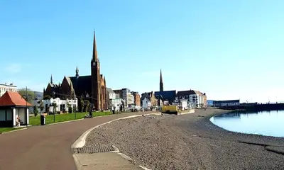 a city street with a river and a church at Sunset of Largs in Largs
