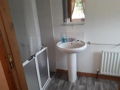 a white bathroom with a sink and a mirror at Beachview Cottage Co. Antrim in Cushendun