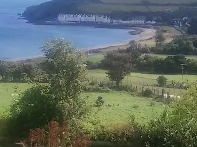 a view of a field and a body of water at Beachview Cottage Co. Antrim in Cushendun