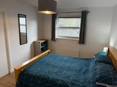 a bedroom with a blue bed and a window at Dunfermline 2 Bed Flat Fully Furnished in Dunfermline