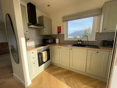 a kitchen with white cabinets and a window at Old Springwell Croft in Onich