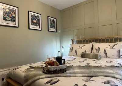 a bedroom with a bed with a tray of food and glasses at Coorie Neuk in Cairnbaan