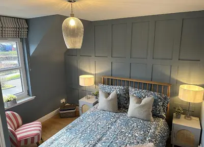 a bedroom with a bed and two tables and two lamps at Coorie Neuk in Cairnbaan