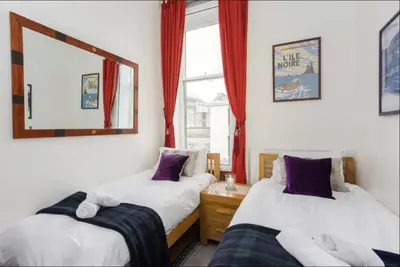 two beds in a room with red curtains and a mirror at Great Location! 2BD,2 Bath in Centre of Edinburgh in Edinburgh