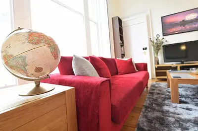 a living room with a red couch and a globe on a table at Great Location! 2BD,2 Bath in Centre of Edinburgh in Edinburgh