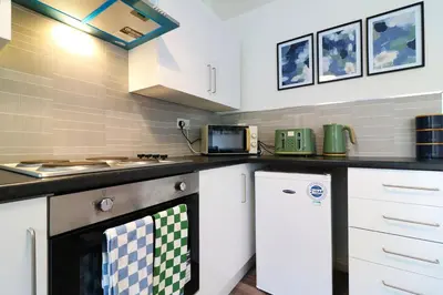 a kitchen with white cabinets and a stove at Signature - Thorn House in Coatbridge