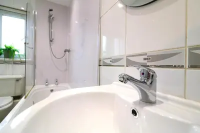 a white bathroom with a sink and a bath tub at Signature - Thorn House in Coatbridge